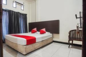 a bedroom with a bed with red pillows and a chair at Hotel O Icha Homestay in Makassar