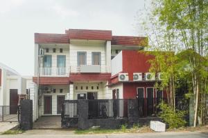 a red and white house with a black fence at Hotel O Icha Homestay in Makassar