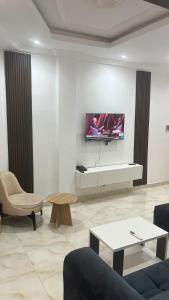 a living room with a tv on a white wall at Hôtel La Miséricorde in Douala