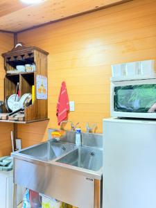 a kitchen with a sink and a microwave on top of a refrigerator at Foresta Karuizawa 7 Glamping & camping for 8 people in Naganohara