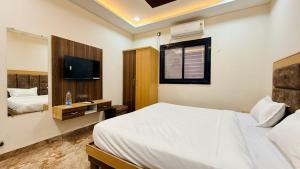 a bedroom with a white bed and a television at Hotel Viraj in Indore