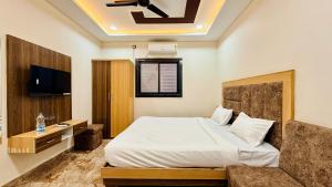 a bedroom with a bed and a tv and a couch at Hotel Viraj in Indore