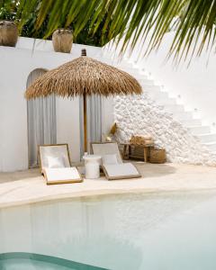 two chairs and an umbrella next to a swimming pool at MAJA Canggu in Canggu