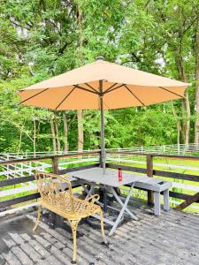 a picnic table with an umbrella and a chair at Foresta Karuizawa 7 Glamping & camping for 8 people in Naganohara +18 photos