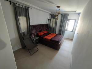 a bedroom with a bed and a chair in a room at Appartement neuf a complex colina smir in Sania Torres