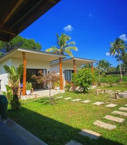 a house with palm trees in front of it at Tropical Aurora Tetebatu in Tetebatu