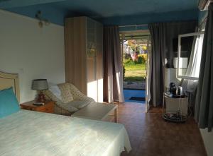 a bedroom with a bed and a chair and a window at Casinhas do Ribeiro in Póvoa de Lanhoso