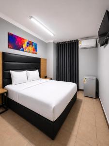 a bedroom with a large white bed and a television at Metro Lodge MP in Durban