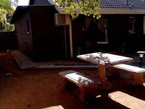 a picnic table and bench in a yard with a basketball hoop at Vhulinganela Guest House in Ellisras +2 photos