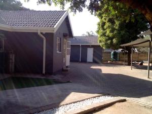 a house with a driveway next to a building at Vhulinganela Guest House in Ellisras