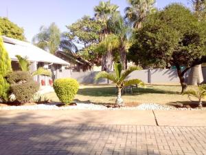 a house with palm trees and a brick driveway at Vhulinganela Guest House in Ellisras