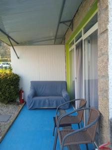 a blue couch sitting on a porch with two chairs at Casinhas do Ribeiro in Póvoa de Lanhoso