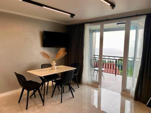 a dining room with a table and chairs and a balcony at Botanic sea view in Batumi