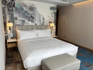 a bedroom with a large white bed and a bench at OZO George Town Penang in George Town