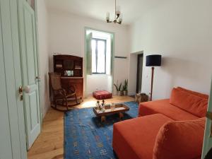 a living room with a red couch and a table at Casa D'avó Souzinha in Ermidas