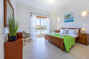 a bedroom with a bed with a green blanket on it at Casa Iguana in Budens +23 photos