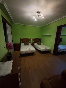 two beds in a room with green walls at Hostal Inés in Boñar