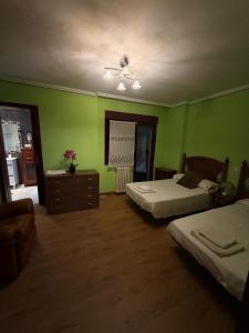 a bedroom with two beds and green walls at Hostal Inés in Boñar