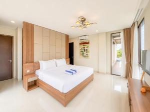 a bedroom with a large white bed and a tv at Tridi Beach Villa by Nagisa Bali in Tanah Lot +22 photos