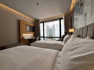 a hotel room with two beds and a large window at OZO George Town Penang in George Town