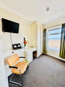 a room with a chair and a desk and a television at Cherish Lewis Sea View Hotel in Blackpool