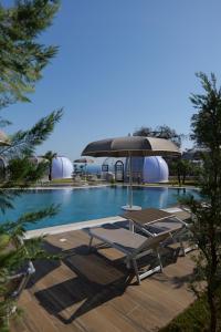 a swimming pool with lounge chairs next to a building at Piccolo Paradiso - Glamping Resort in Shëngjin