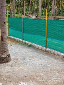 a fence with a tree in front of it at Coco Kudil - FARM STAY in Salem