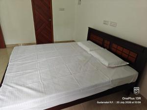 a bedroom with a large bed with white sheets at Coco Kudil - FARM STAY in Salem +1 photo