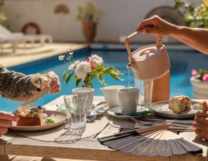 Eine Gruppe von Menschen sitzt um einen Tisch und isst. in der Unterkunft Hôtel La Villa Juan Beach in Juan-les-Pins