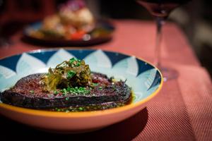 a plate of food on a table with a wine glass at Chambres à la Table du Curé in Cucugnan