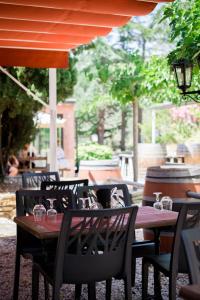 a wooden table and chairs at an outdoor restaurant at Chambres à la Table du Curé in Cucugnan