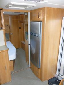 a small kitchen with a refrigerator and wooden cabinets at Muzeum PRL noclegi in Ostróda