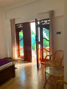 a room with doors and a glass table and chairs at Villa Nadika in Beruwala