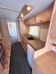 a small kitchen with wooden cabinets and a sink at Skegness Seaside Escape in Ingoldmells