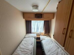 a small room with two beds and a window at Skegness Seaside Escape in Ingoldmells