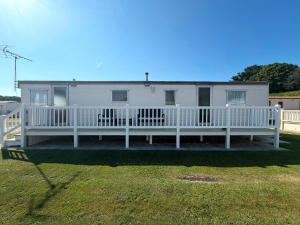 a white house with a porch and a white fence at Skegness Seaside Escape in Ingoldmells