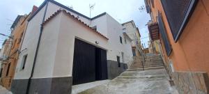 a white building with a black door on a street at Apartamento Turístico La Miranda in Elche de la Sierra