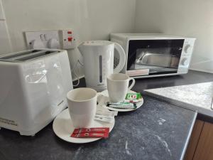 a kitchen counter with two cups and a microwave at Stylish Bolton Stay Parking Walk to Town Centre in Farnworth