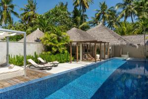 a pool at a resort with chairs and umbrellas at Niva Kuramathi Maldives in Rasdhoo