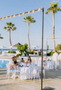 a group of people sitting at tables in front of a pool at Thalasses in Adelianos Kampos