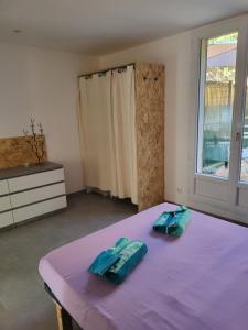 a bedroom with a purple bed with two towels on it at Paisible T2 climatisé avec jardinet in Béziers