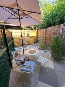 a patio with a table and chairs and an umbrella at Paisible T2 climatisé avec jardinet in Béziers +13 photos