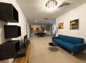 a living room with a blue couch and a tv at Bora Bora Ibiza Malta Resort - Music Hotel - Adults Only 18 plus in St. Paul's Bay