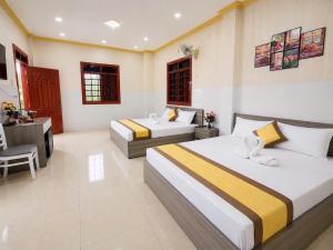 a hotel room with two beds and a desk at Viora Hotel in Ấp Phước Thiện