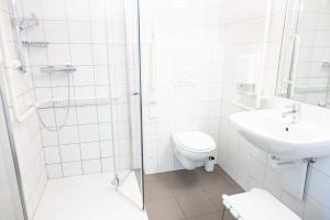 a white bathroom with a toilet and a sink at Junges Hotel Hard am Bodensee in Hard