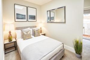 a bedroom with a white bed and two windows at The Madison Garden in Whitby