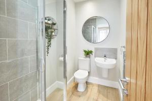 a bathroom with a toilet and a sink and a mirror at The Madison Garden in Whitby +6 photos