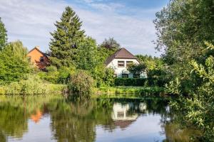 a house on the water with trees and a lake at Anker in Papendorf