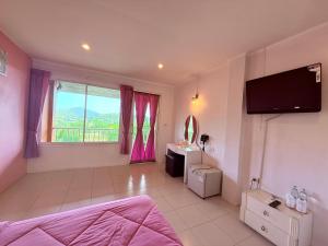 a bedroom with a bed and a tv on the wall at Baan Suan Rojjana in Muak Lek District