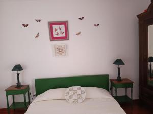 a bed with a green headboard and two tables with lamps at Casa BENVINDHA in Degolados